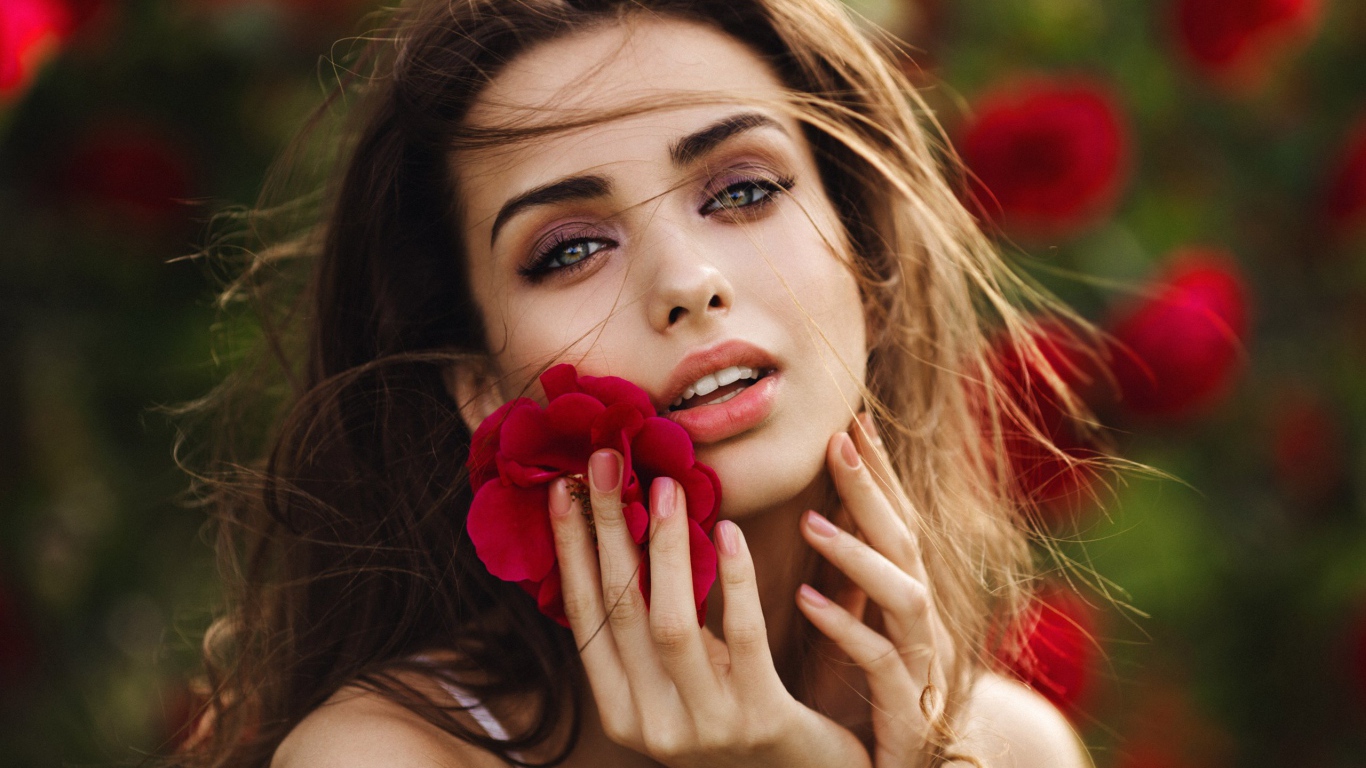 Красивая девушка шатенка с цветком у лица