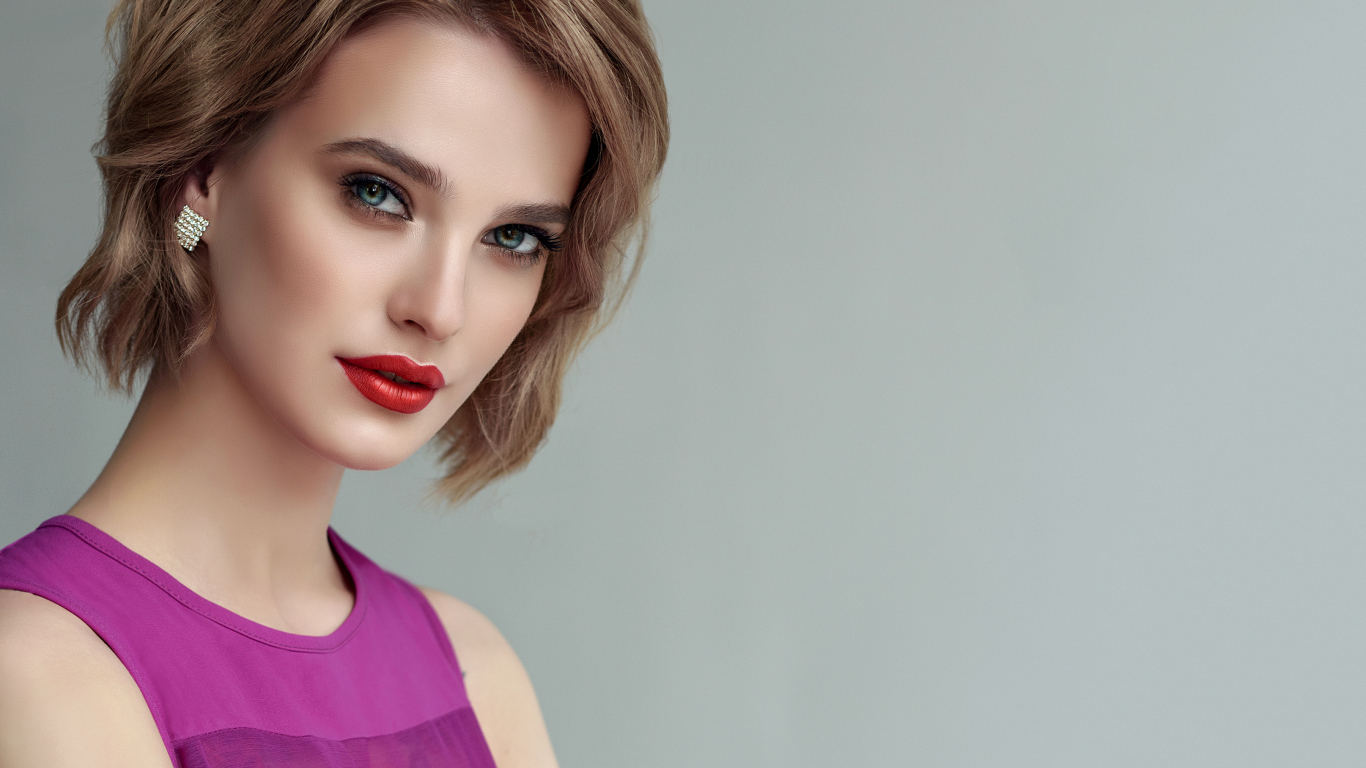 Красивая девушка шатенка с короткой стрижкой на сером фоне