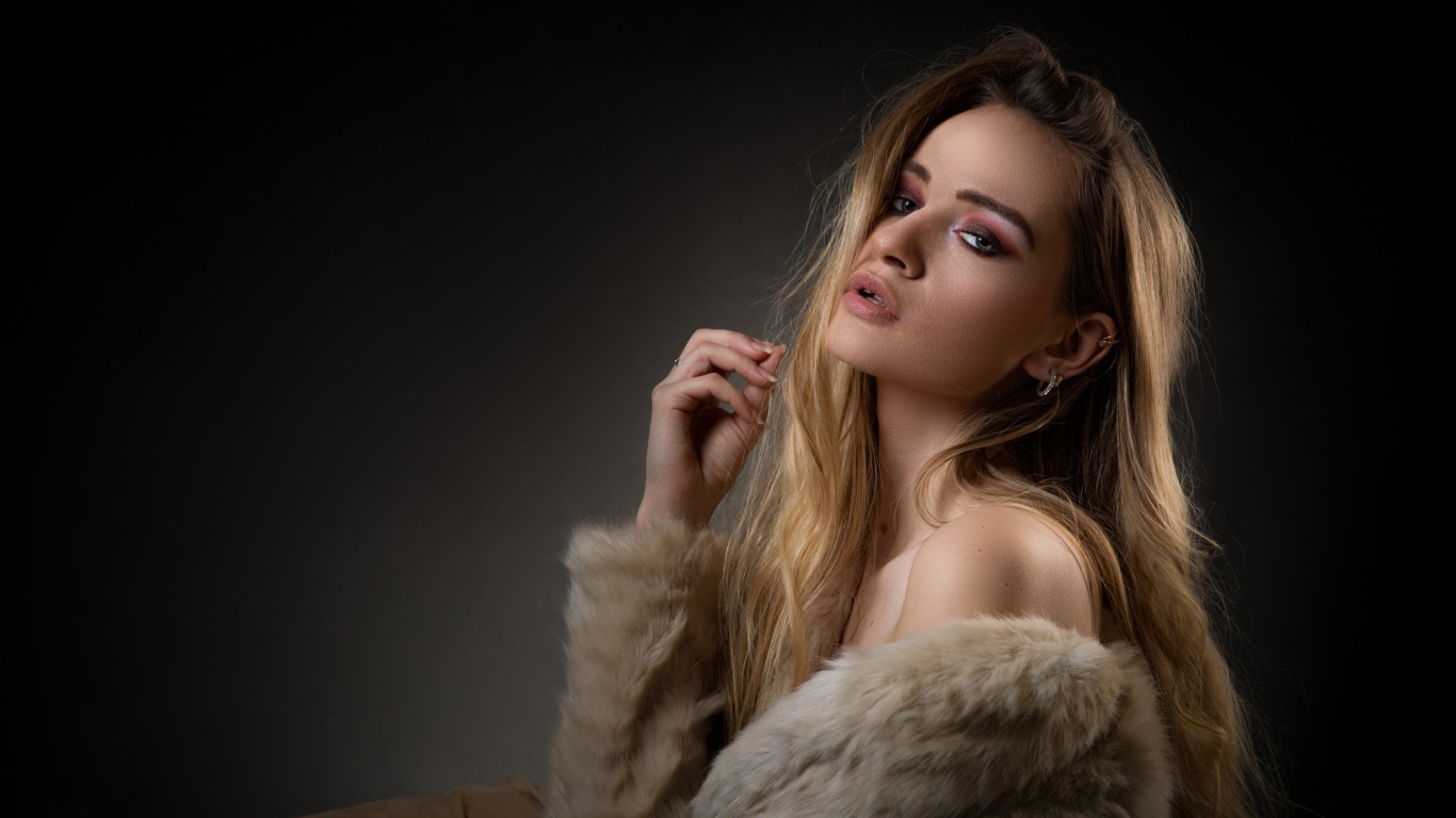 Красивая девушка в шубе на сером фоне