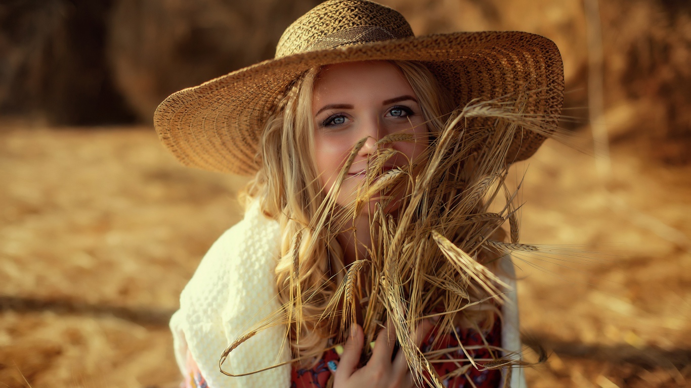 Красивая девушка в шляпе с колосьями в руке