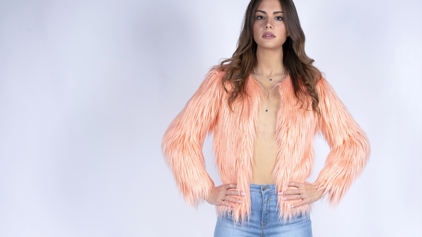 Красивая девушка в розовой шубе и джинсовых шортах