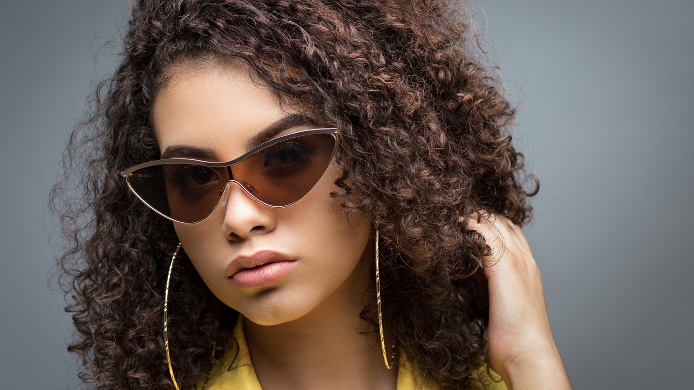 Красивая девушка в солнечных очках на сером фоне