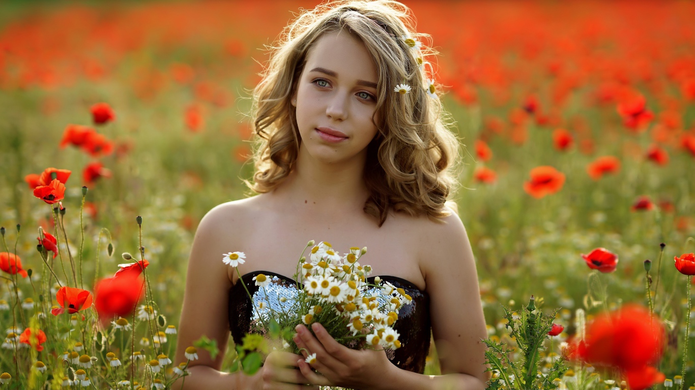 Красивая девушка с букетом ромашек на поле с маками