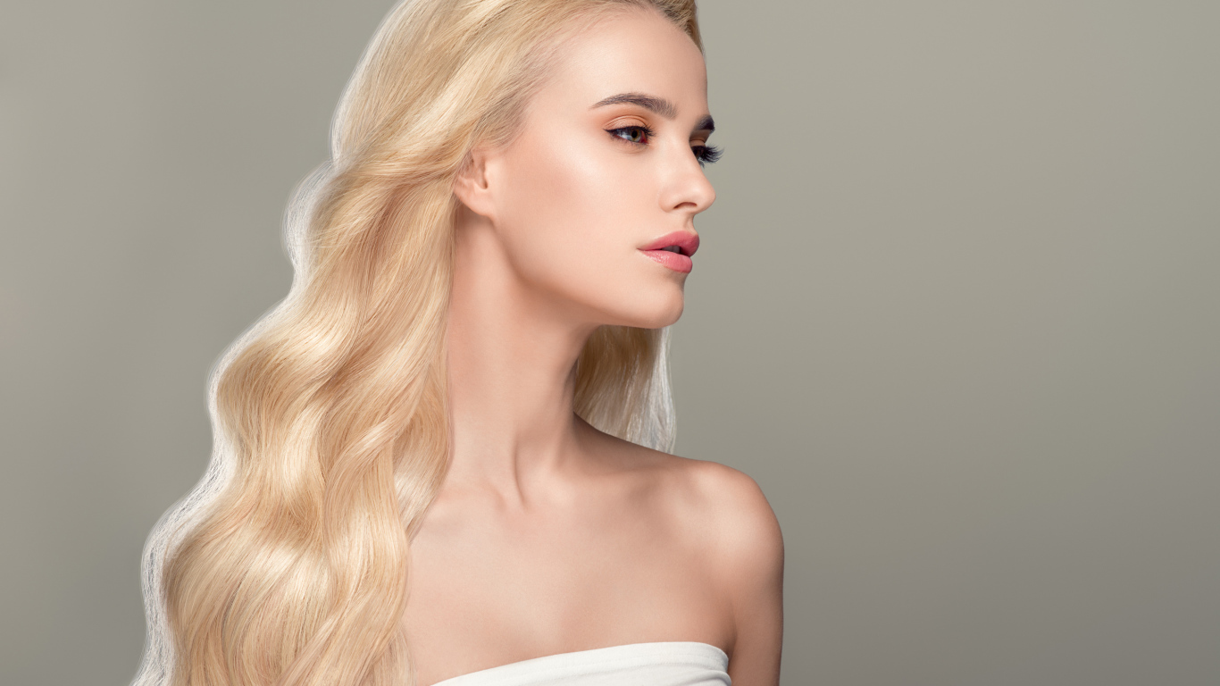 Красивая длинноволосая девушка блондинка на сером фоне