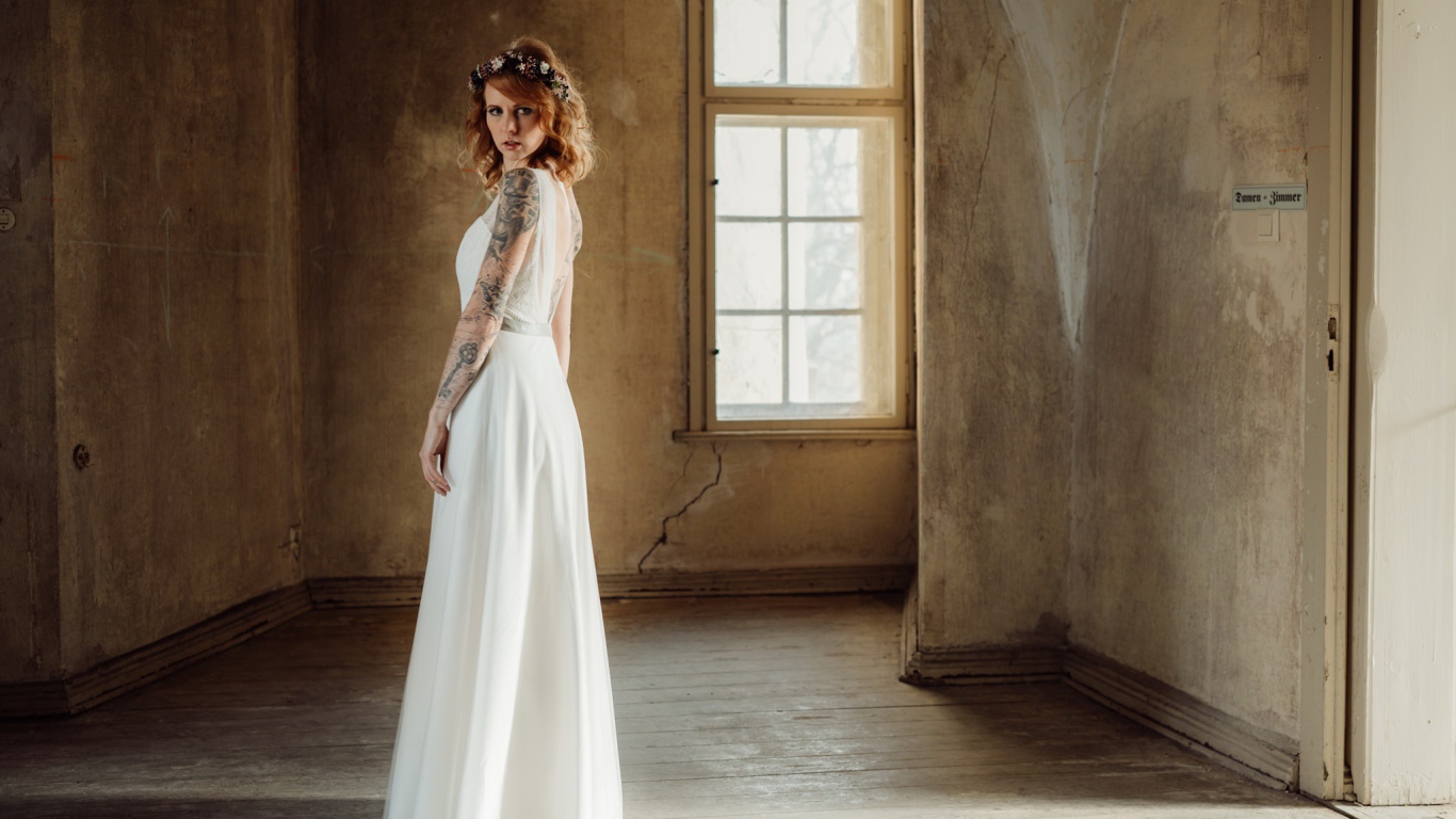 Красивая рыжеволосая девушка в белом платье с  татуировками на теле 