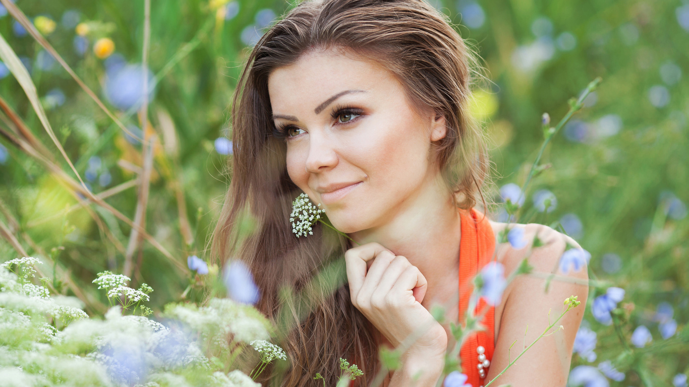 Красивая нежная девушка лежит в цветах на поле