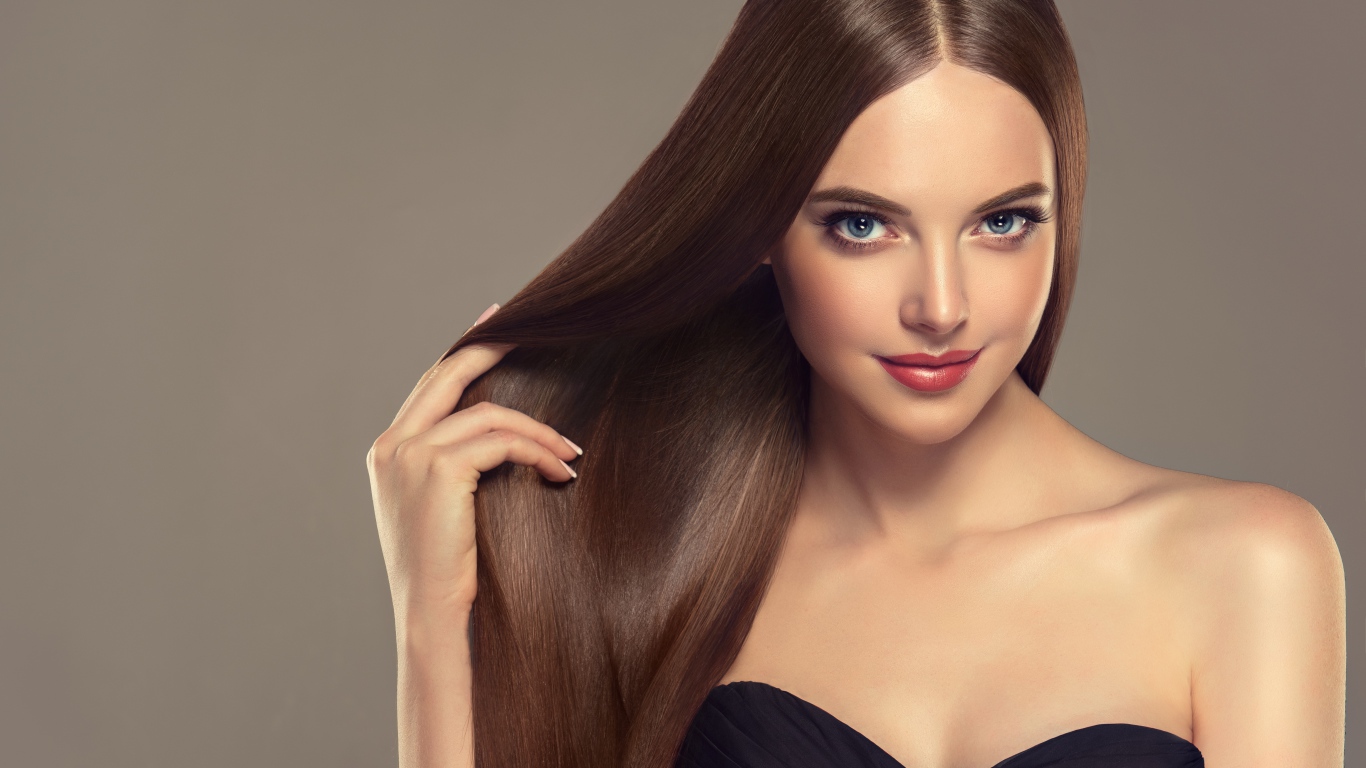 Красивая нежная длинноволосая голубоглазая девушка на сером фоне