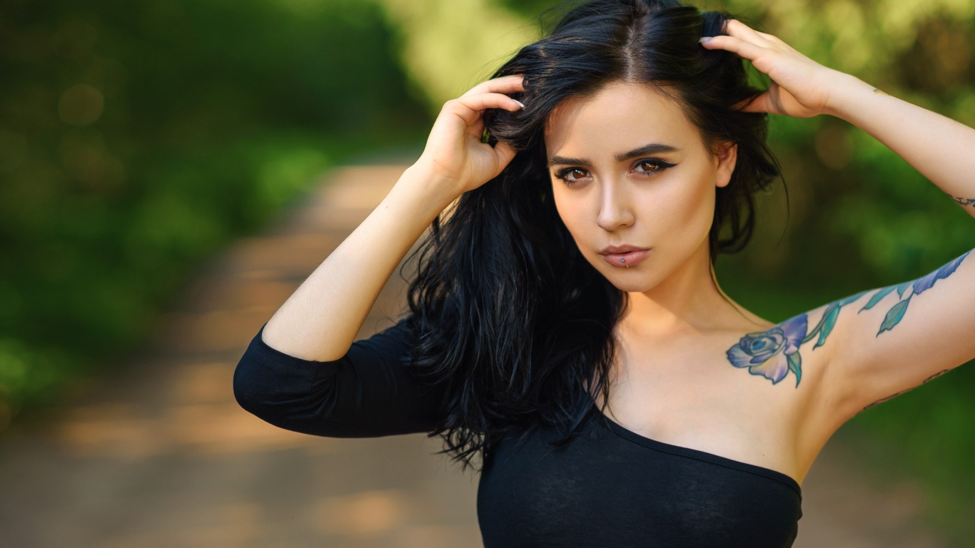 Красивая молодая девушка в черном с татуировкой на руке