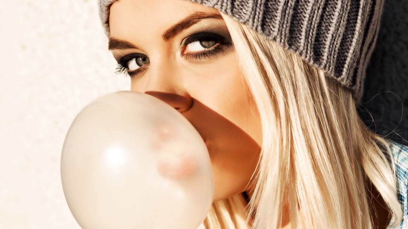 Девушка блондинка с жвачкой во рту крупным планом