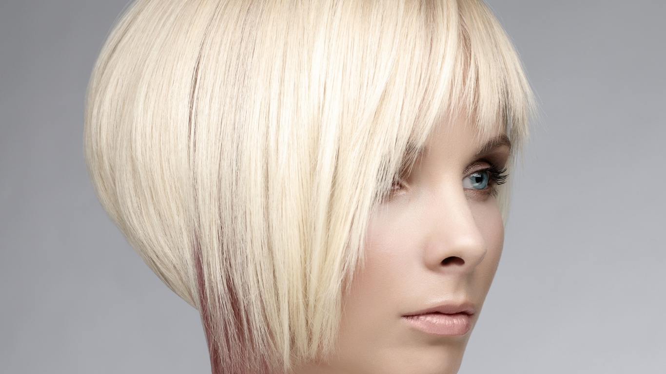 Голубоглазая девушка блондинка с короткой стрижкой на сером фоне