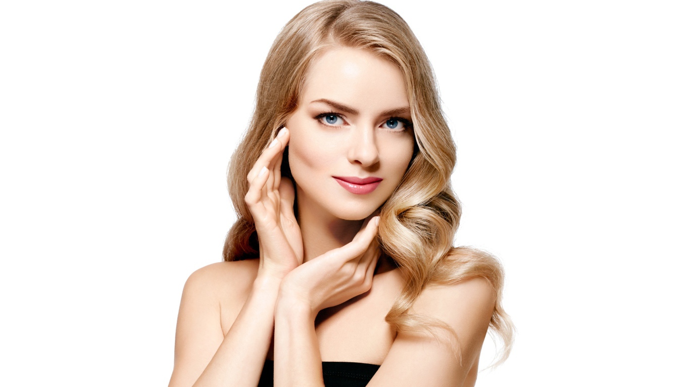 Голубоглазая блондинка с руками у лица на белом фоне