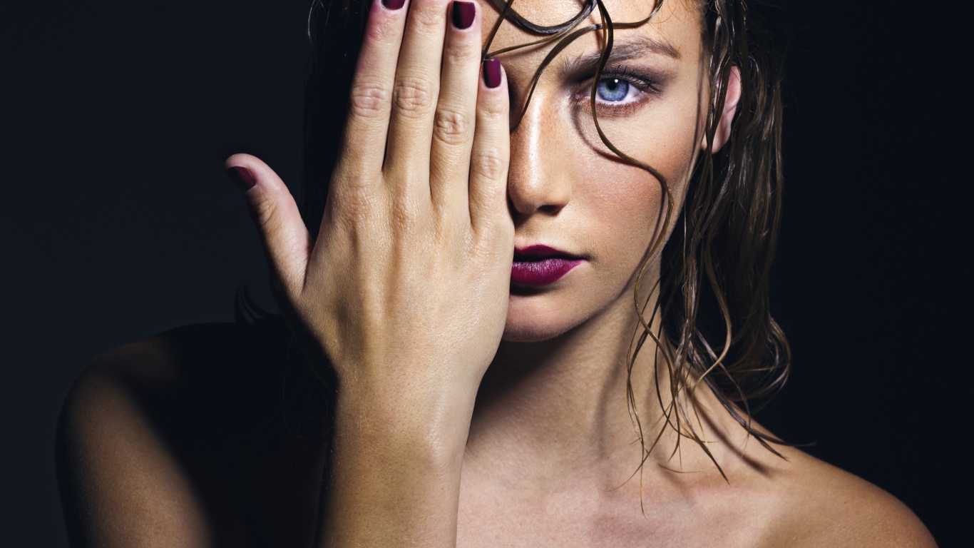 Голубоглазая девушка закрывает лицо рукой