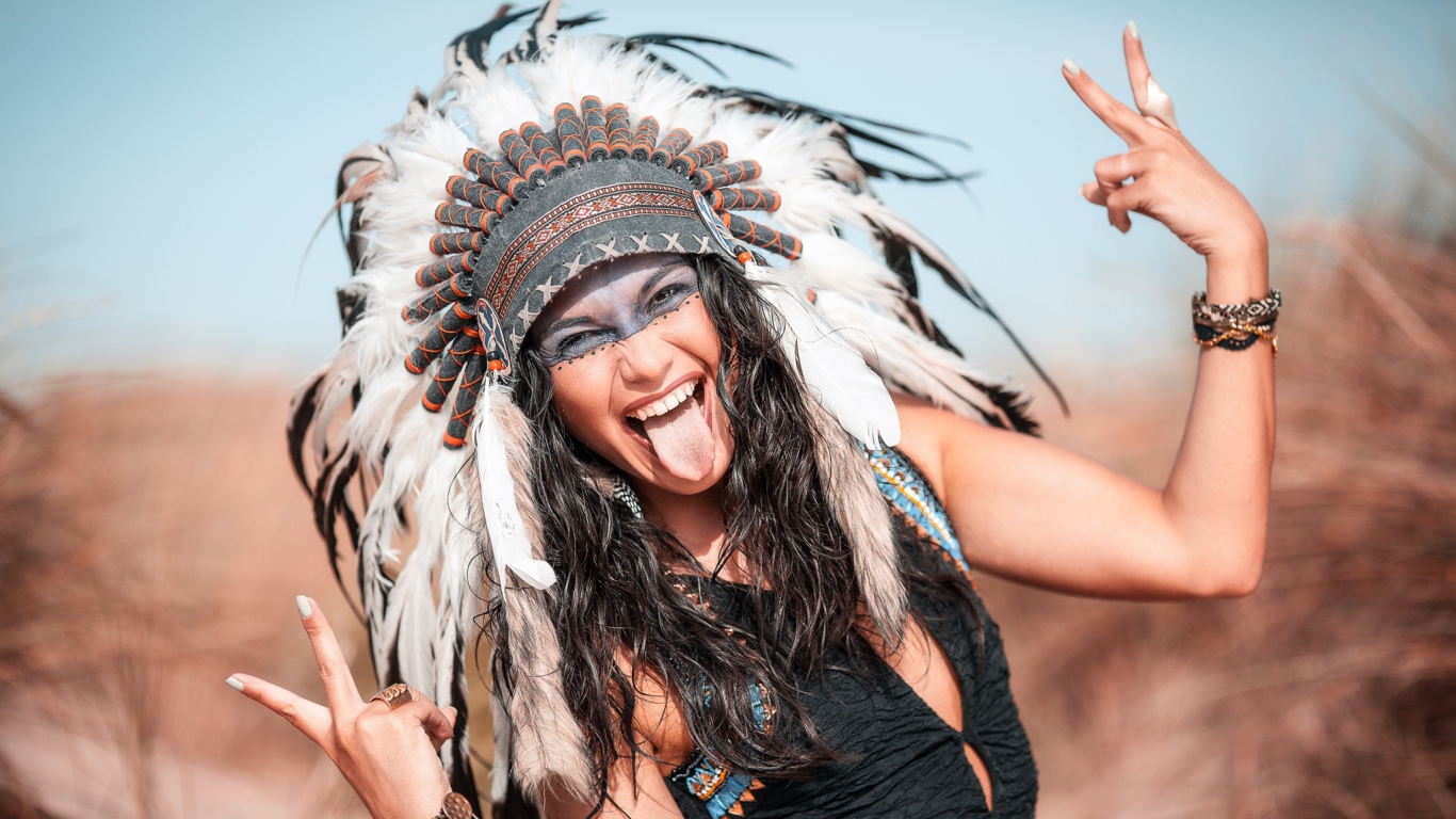 Веселая девушка с высунутым языком в костюме индейца