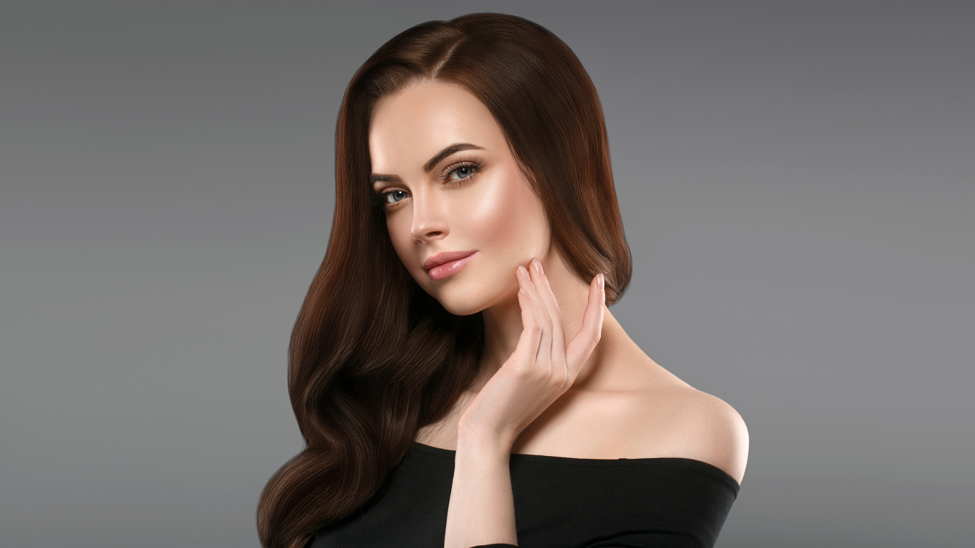 Нежная длинноволосая шатенка в черном платье на сером фоне