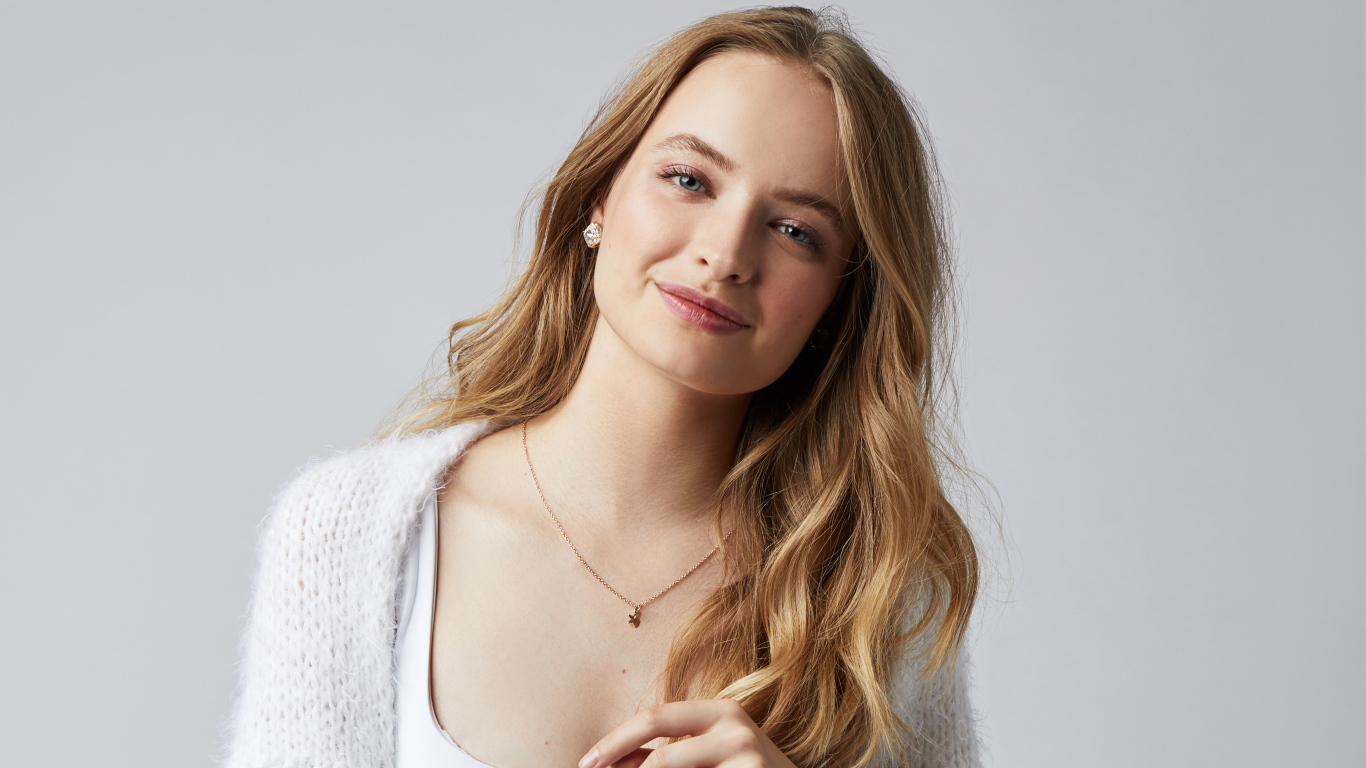 Нежная улыбающаяся голубоглазая девушка на сером фоне