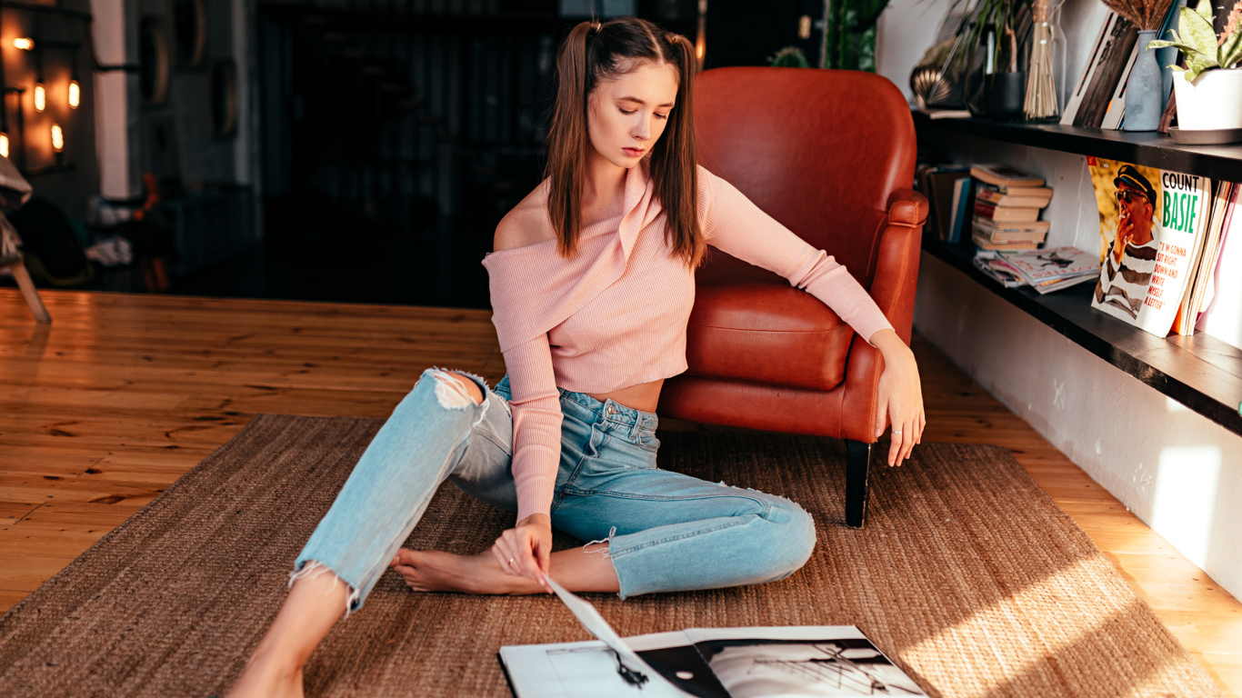 Девушка читает журнал на полу у кожаного кресла