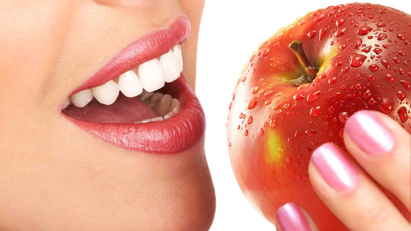 Девушка с красивыми белыми зубами кусает яблоко