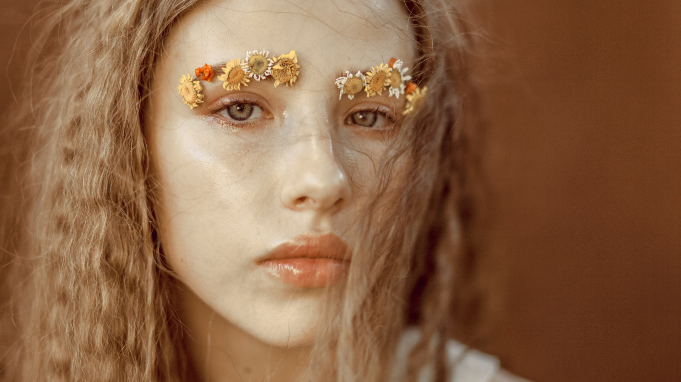 Девушка с цветами на бровях крупным планом