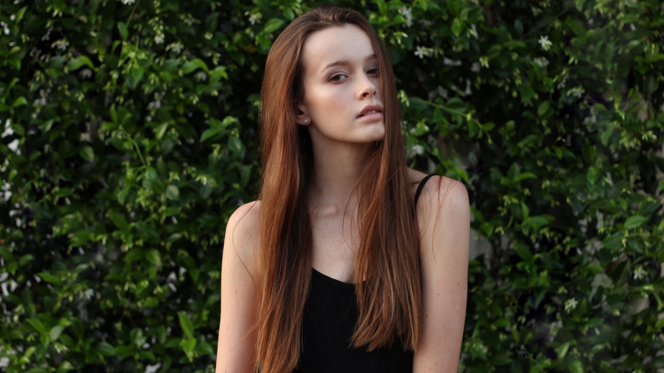 Длинноволосая шатенка на фоне зеленых зарослей