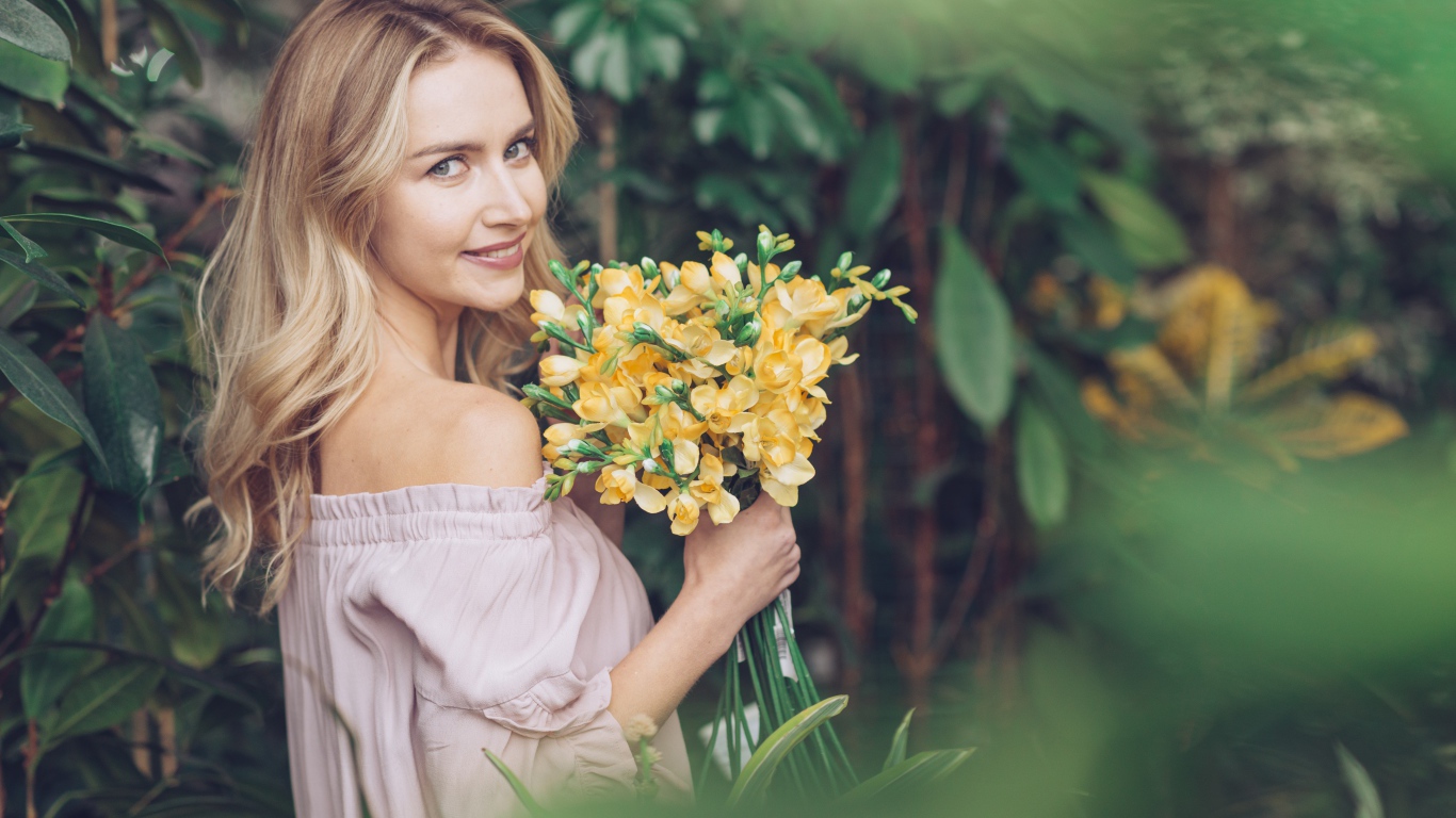Улыбающаяся блондинка с букетом хризантем в руках