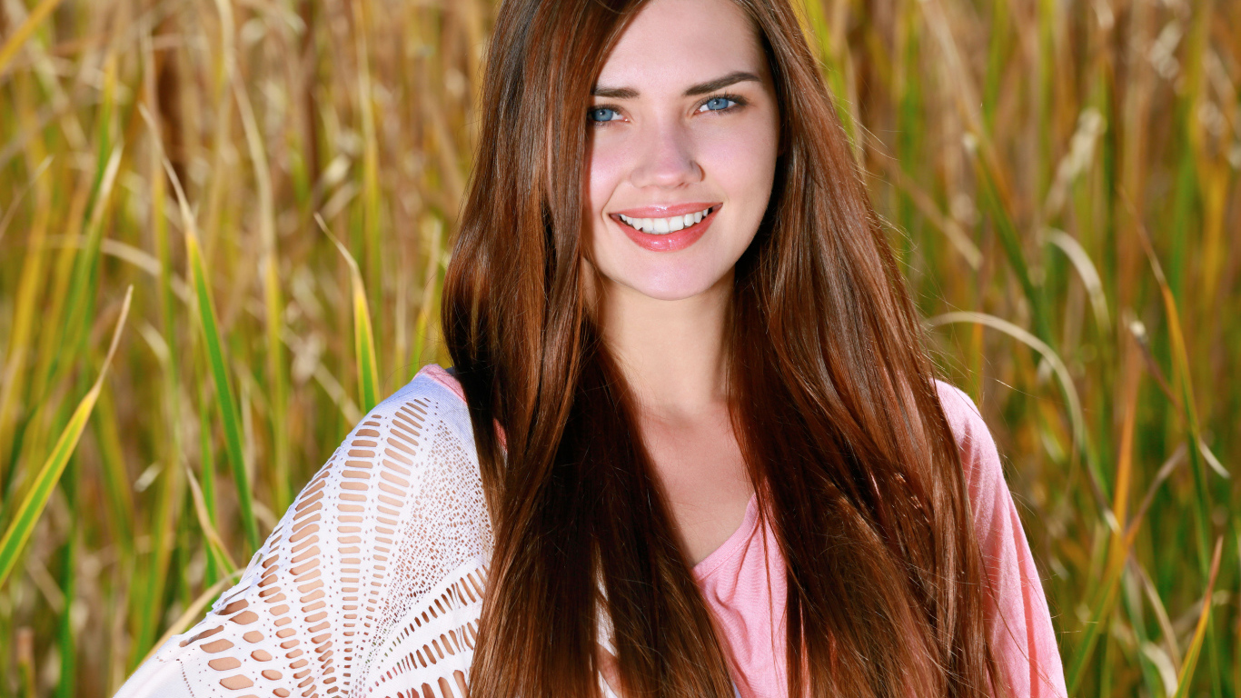 Улыбающаяся голубоглазая шатенка на поле