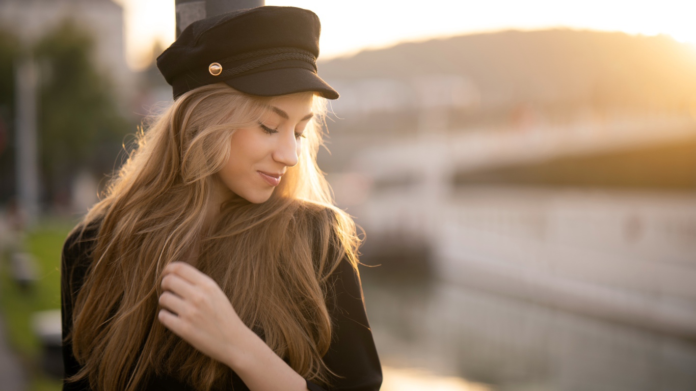 Нежная девушка в черной кепке в лучах солнца
