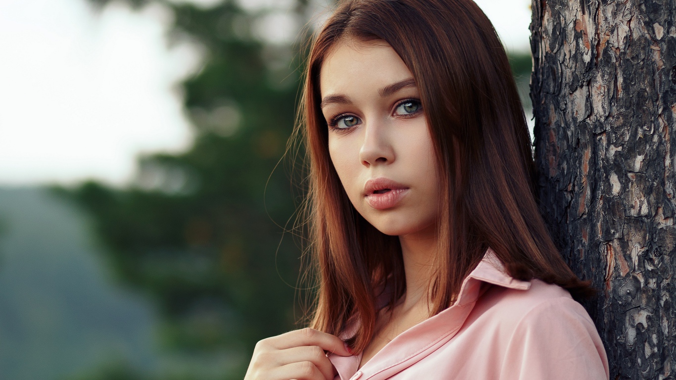 Нежная девушка стоит у дерева