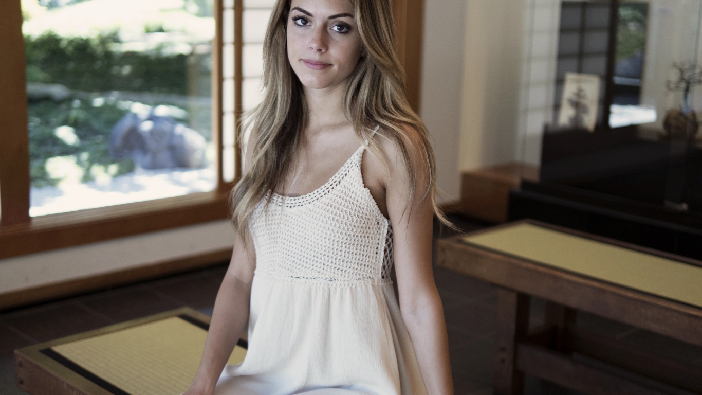 Девушка в белом сарафане сидит на лавке 