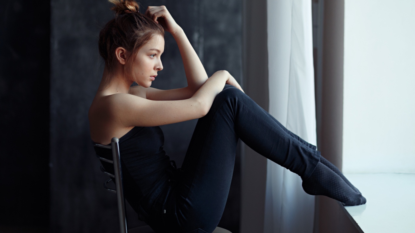 Девушка в черном наряде сидит на стуле