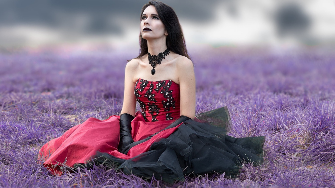 Девушка с макияжем в красивом платье сидит на траве