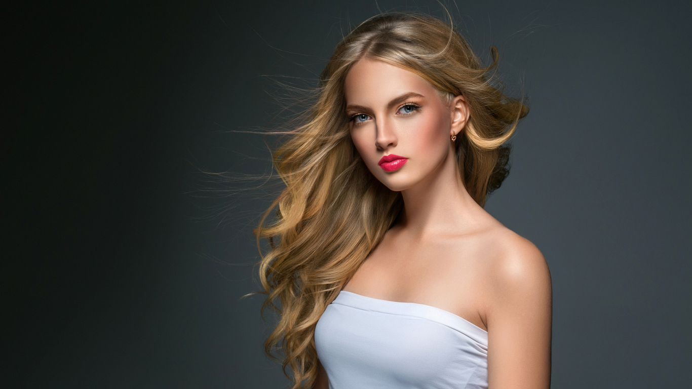 Молодая красивая голубоглазая блондинка на сером фоне