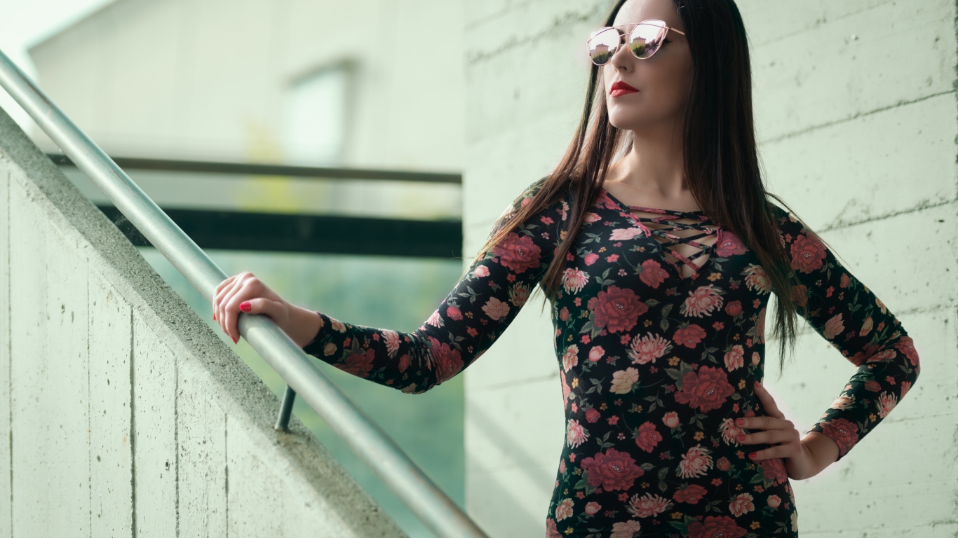 Молодая девушка в солнечных очках стоит на ступеньках