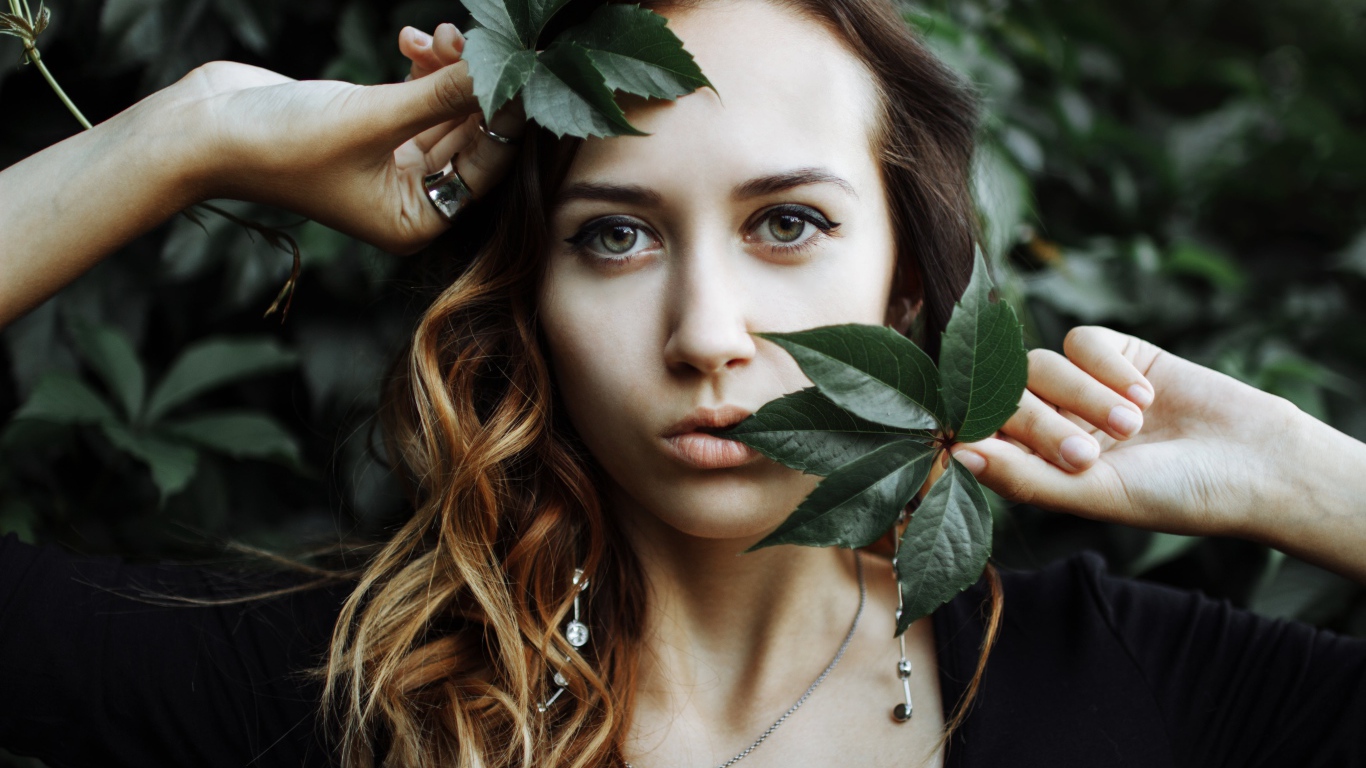 Молодая девушка с зелеными листьями в руках 