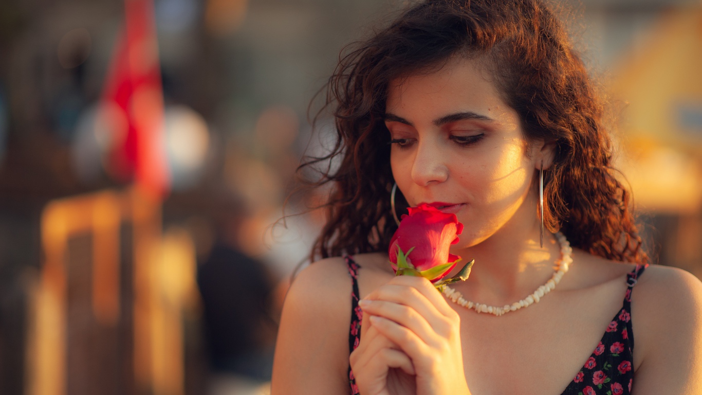 Молодая нежная девушка с красной розой в руке