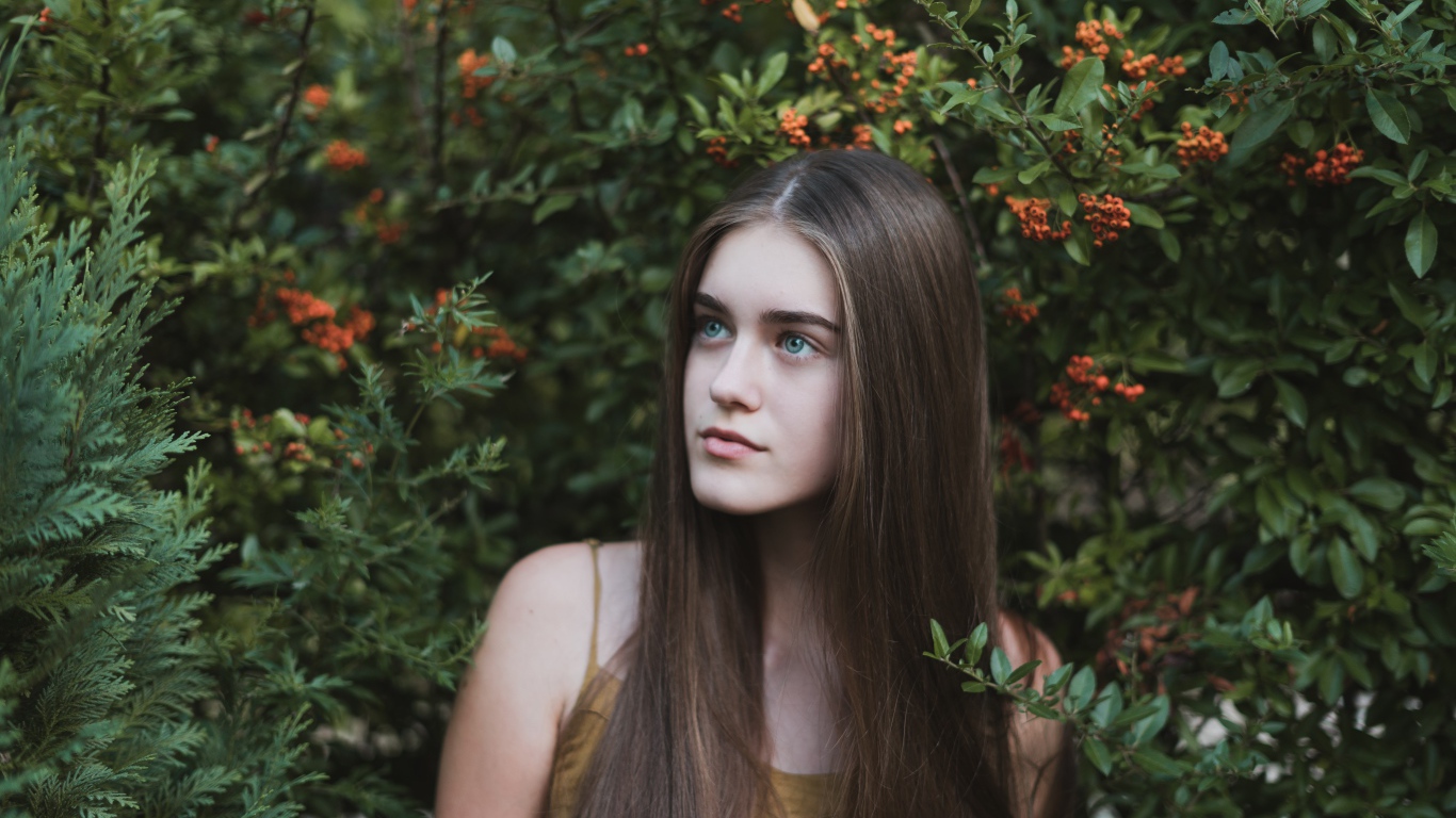 Молодая нежная девушка с длинными волосами в зеленых зарослях 