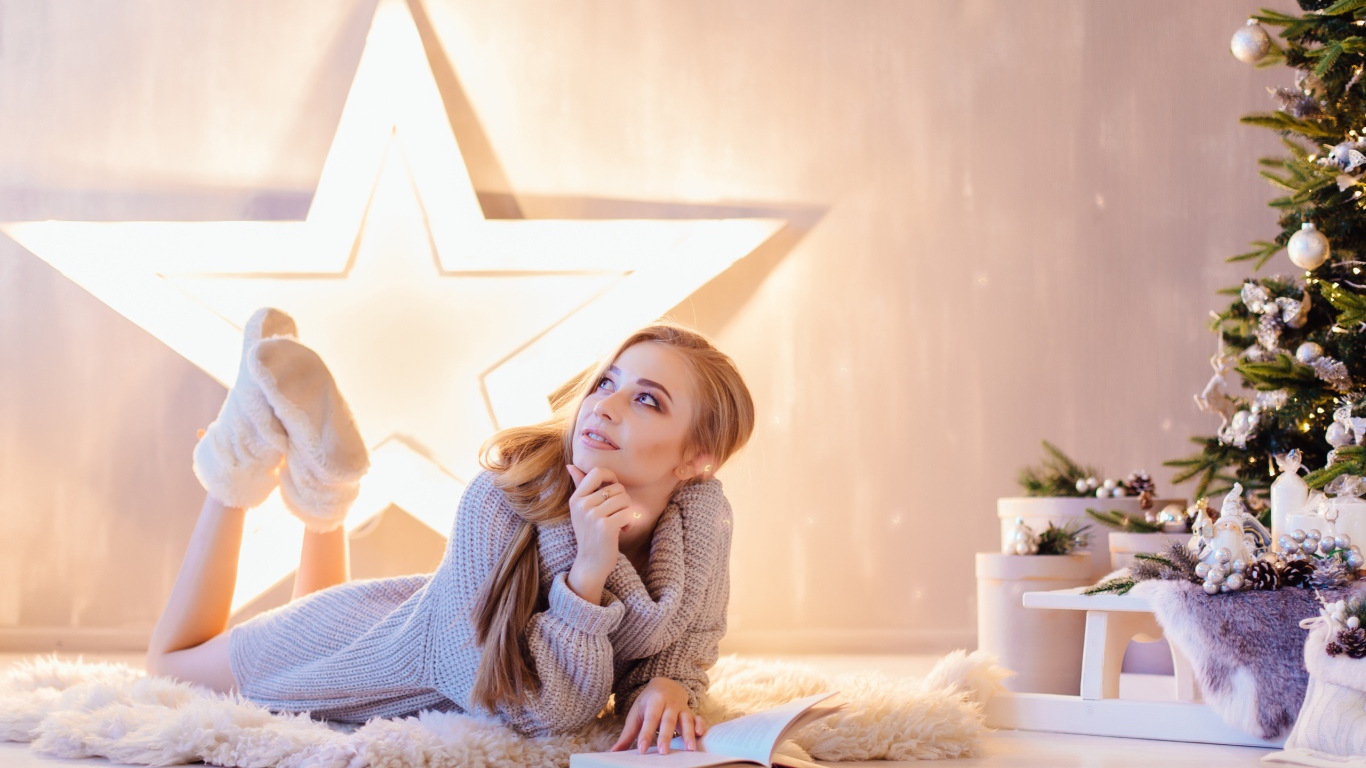 Красивая девушка читает книгу у новогодней елки