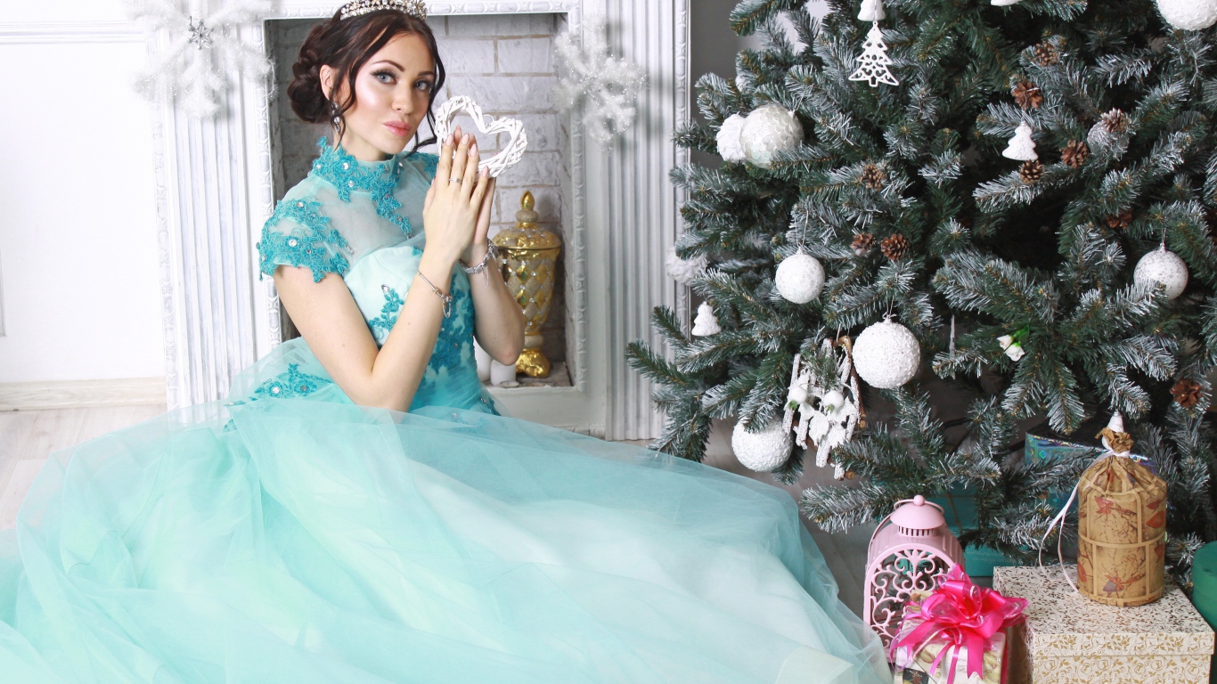 Young girl in a beautiful blue dress near the New Year tree