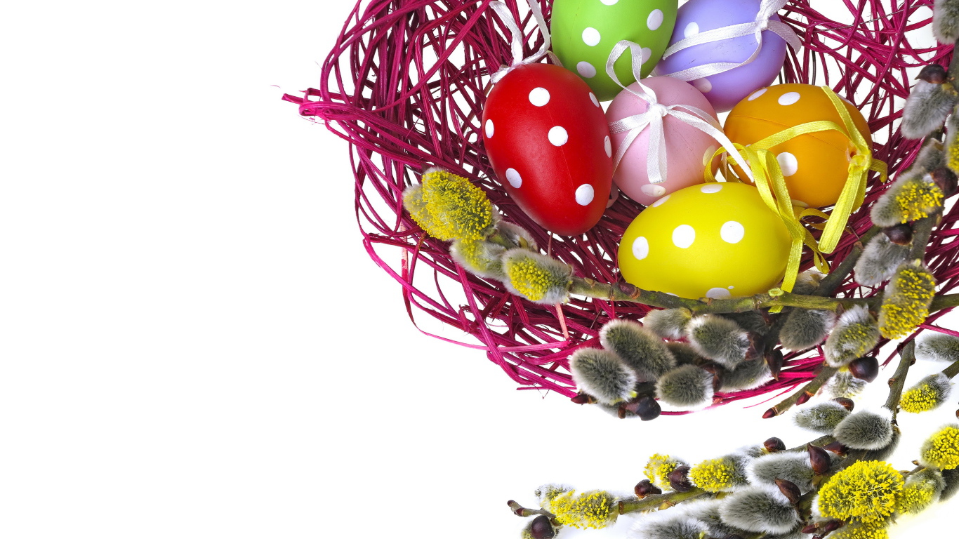 Крашеные пасхальные яйца в гнезде на белом фоне с веткой вербы