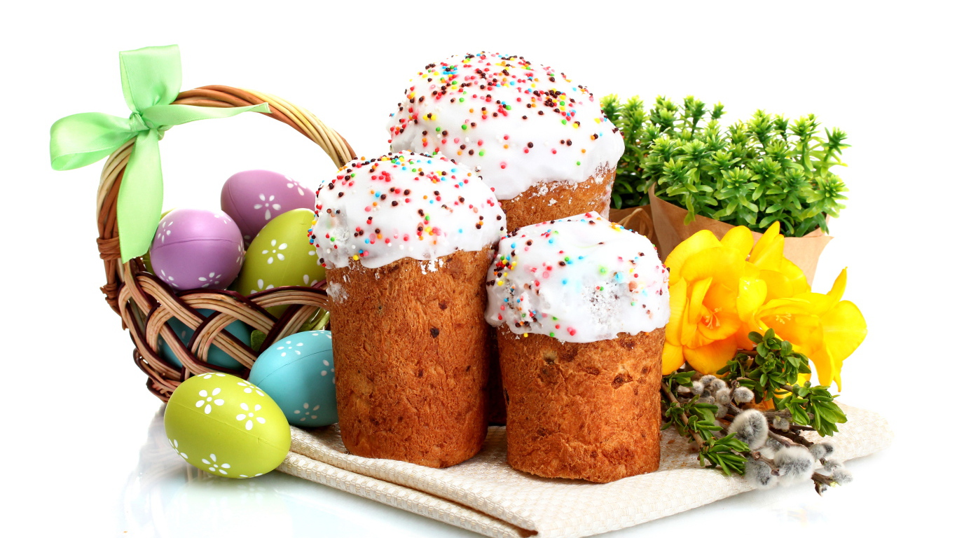 Три сладких кулича на белом фоне с цветами и крашеными яйцами к празднику Пасха