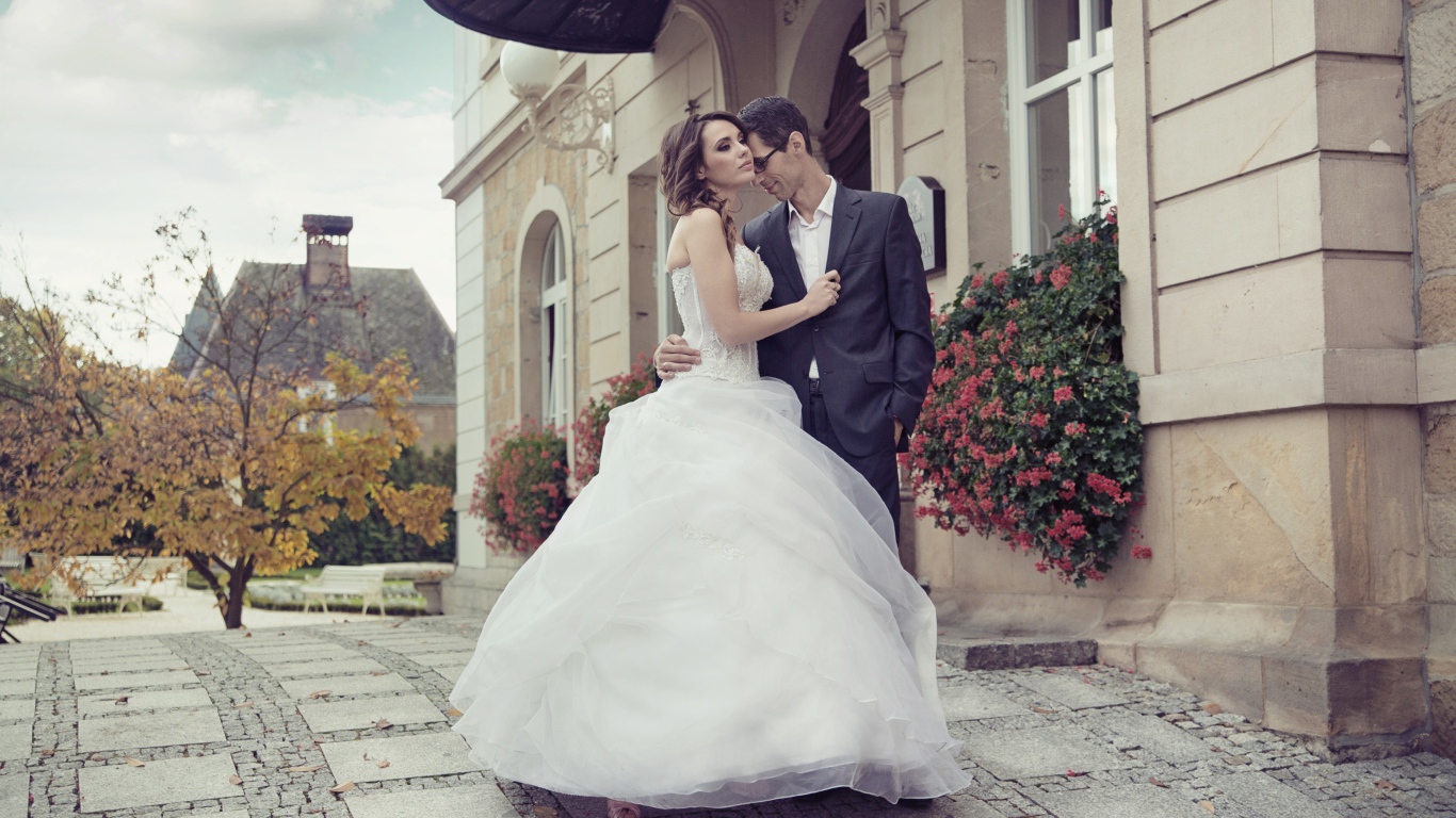 Жених и невеста стоят у здания 