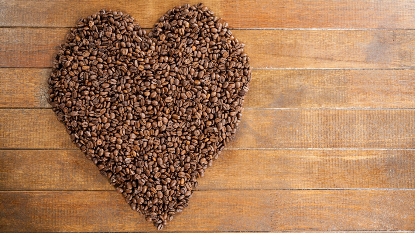 Большое сердце из кофейных зерен на деревянном столе