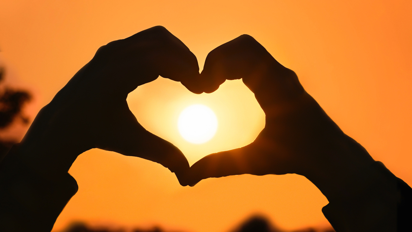 Сердце руками на фоне солнца в небе