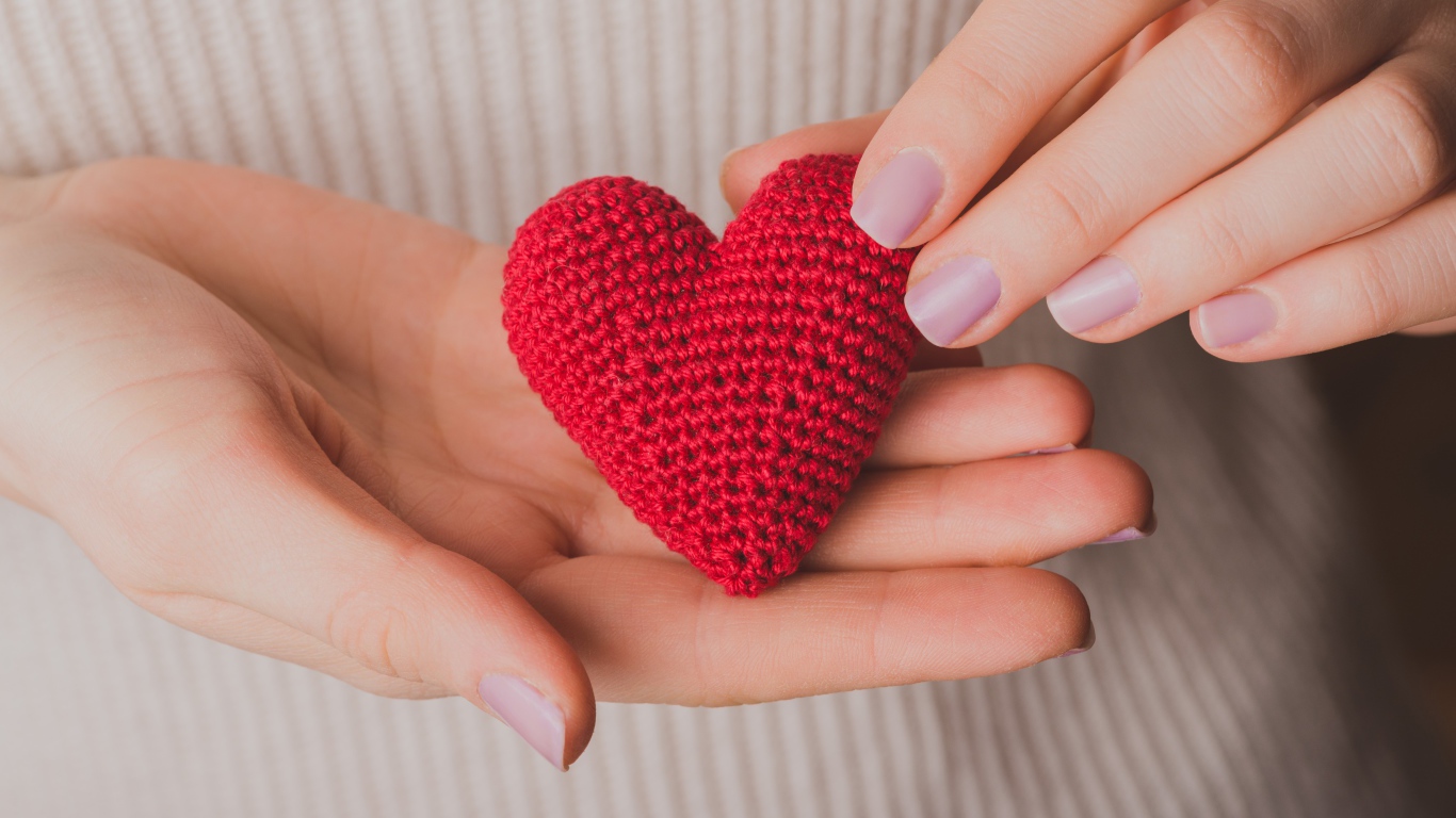 Красное вязаное сердце в руках у девушки