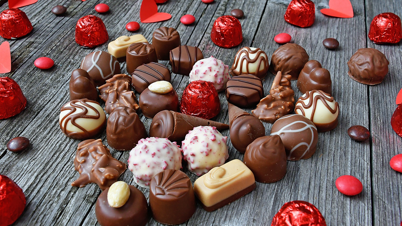 Сладкое сердце из шоколадных конфет на деревянном столе