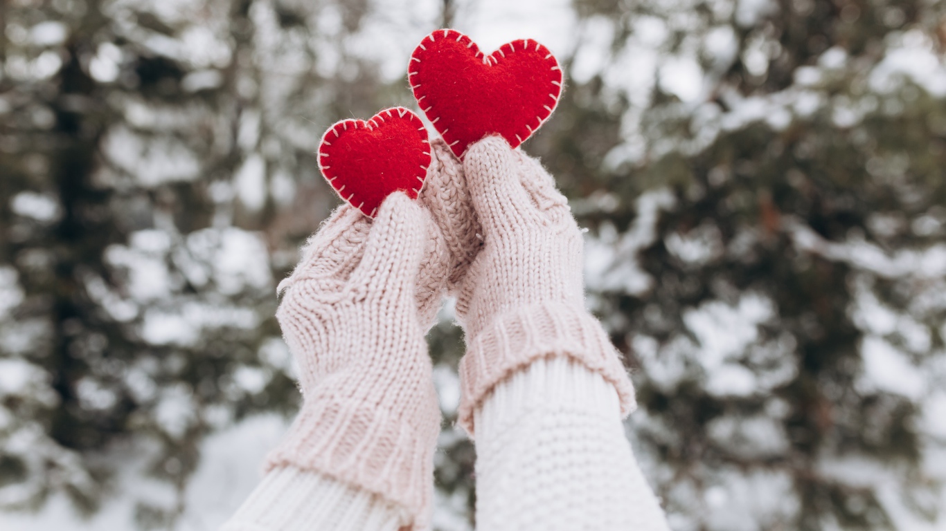 Два красных сердечка из ткани в руках у девушки 