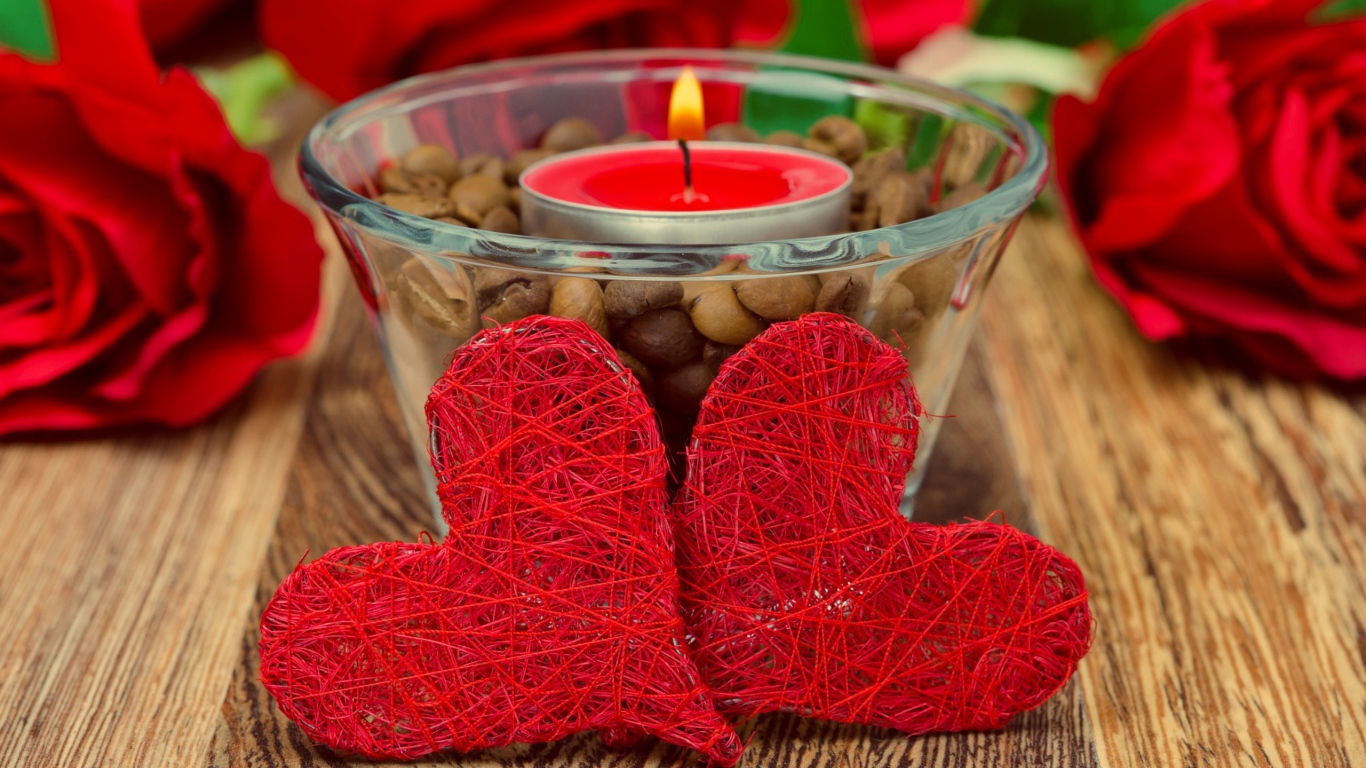 Два красных плетеных сердца на столе с зажженной свечой