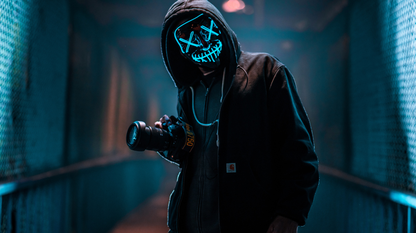 A guy in an anonymous neon mask with a camera