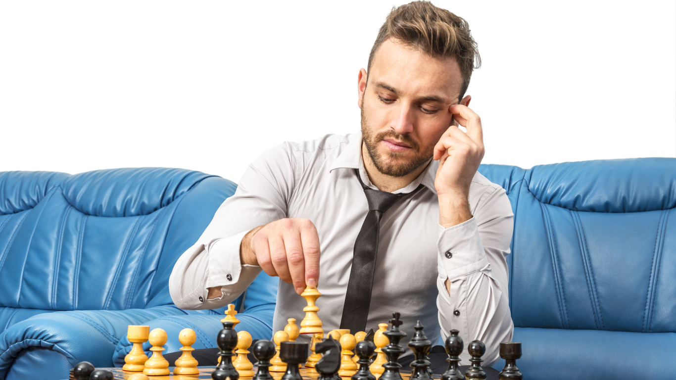 Мужчина играет в шахматы на синем диване