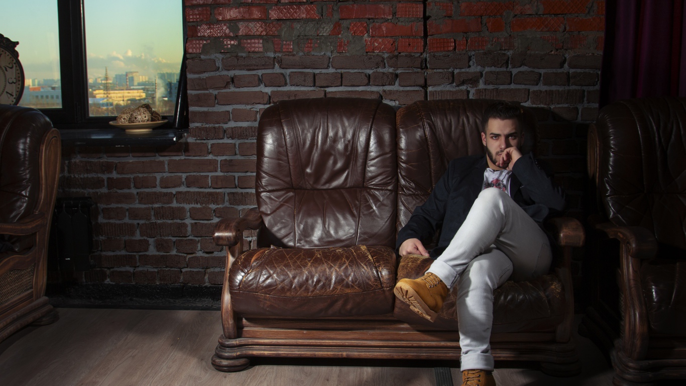 Стильный мужчина сидит в кожаном кресле 