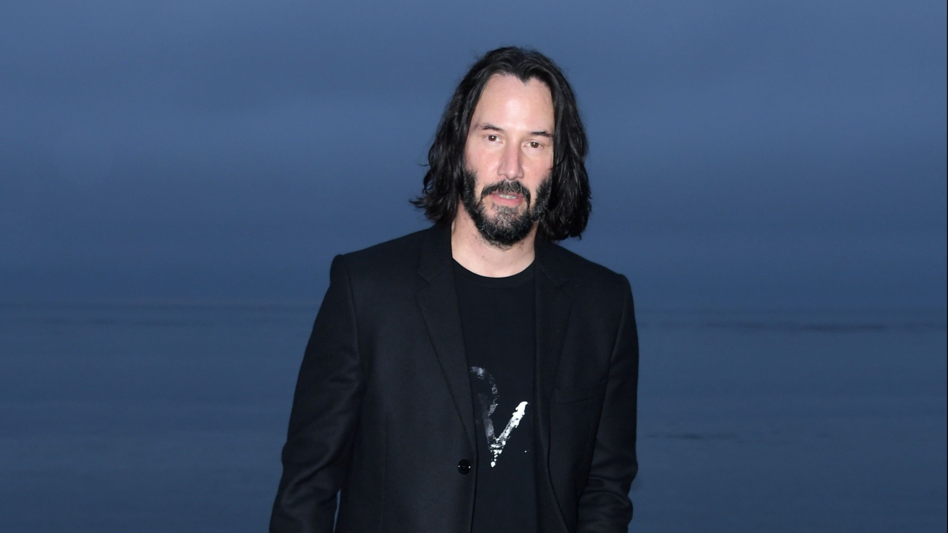 Актер Киану Ривз с бородой на синем фоне